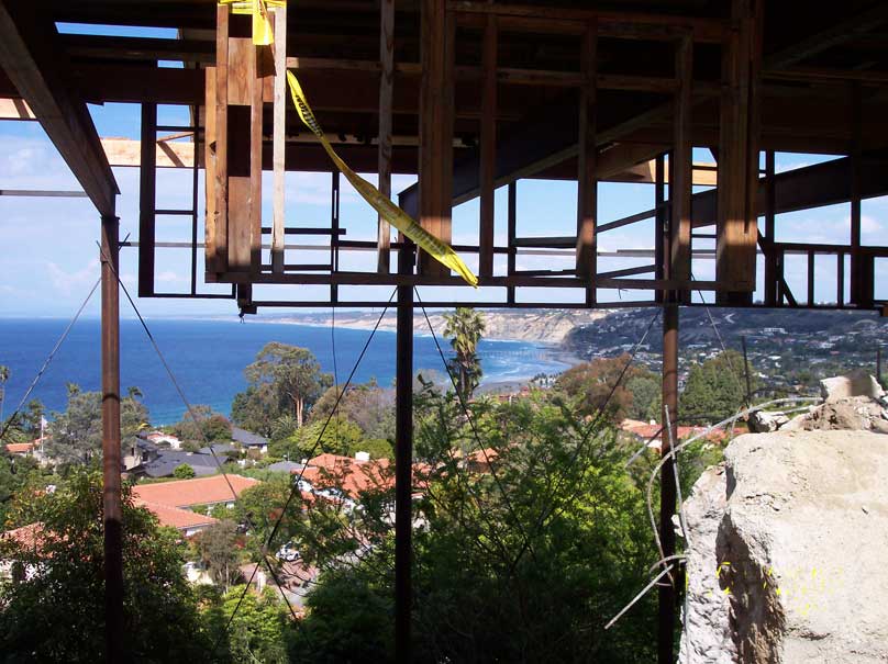 An underside view of a custom shoring project supporting renovations for a home built on a hillside overlooking the ocean.