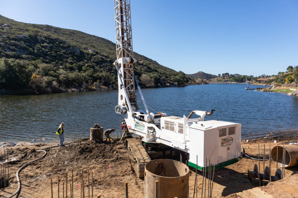 A pair of construction workers overseeing a riverside caisson drilling operation for a pool project in San Diego, CA.