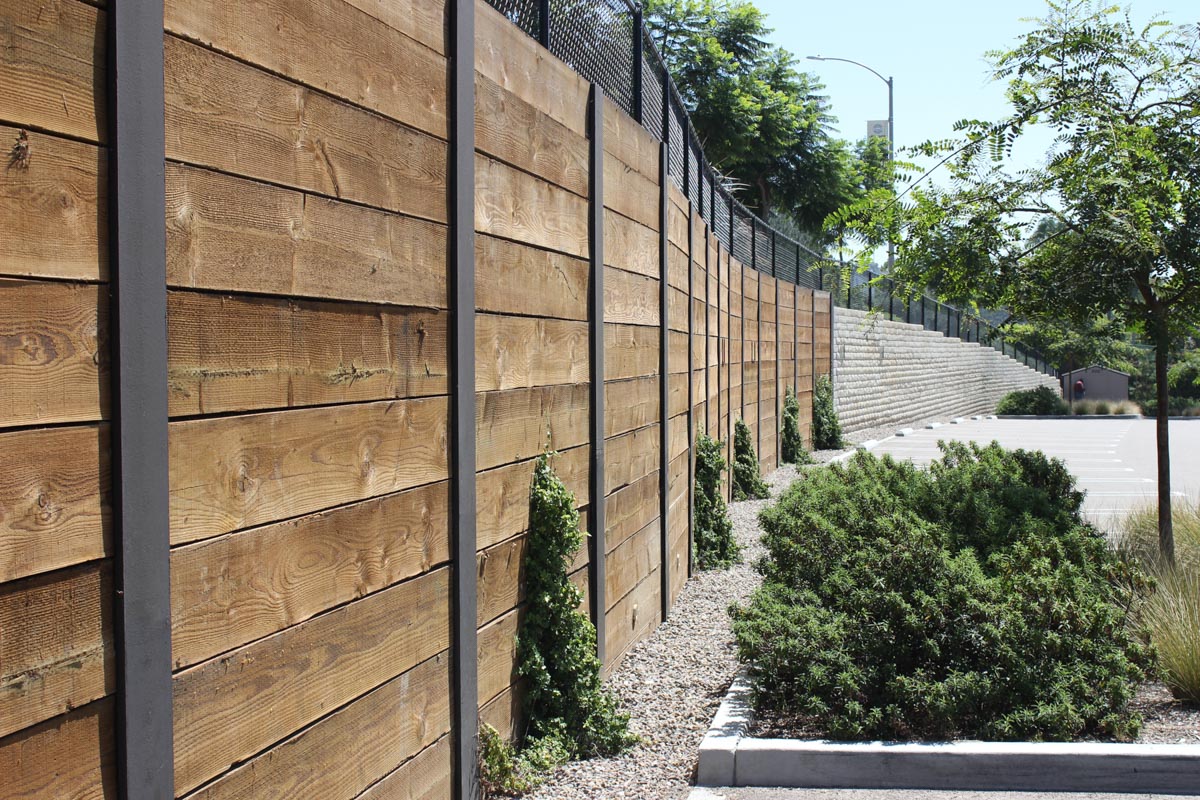 A completed permanent curved shoring wall with pressure-treated wood planks and exposed steel beams in San Diego, CA.
